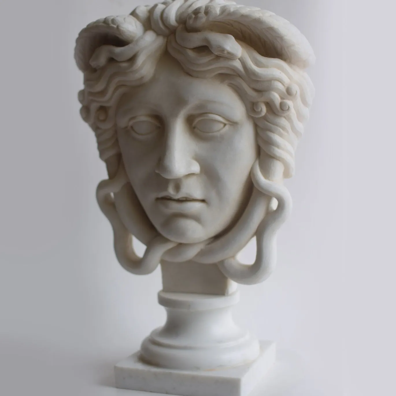 Scultura Medusa in marmo bianco di Carrara su trapezoforo